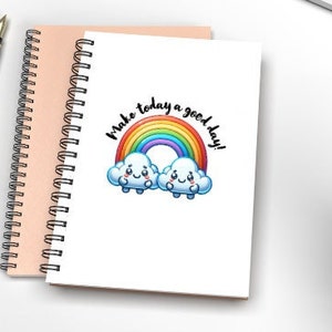 Könnte beinhalten: Ein weißes Notizbuch mit einem Regenbogen und zwei Wolken mit Gesichtern. Der Text "Make today a good day!" steht über dem Regenbogen.