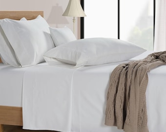 May include: White bed linens with a brown cable knit throw blanket on top. The bed is made with a white fitted sheet, a white flat sheet, and two white pillowcases.