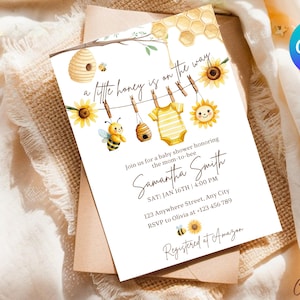 May include: Baby shower invitation with a watercolor design. The invitation features a bee theme with sunflowers, a onesie, and the text "a little honey is on the way." The invitation is on a white background.