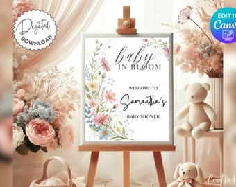 May include: A baby shower sign on a wooden easel, featuring the text "baby in bloom" and "Welcome to Samantha's Baby Shower." The sign is decorated with watercolor flowers in pink, yellow, and blue. A teddy bear and a bunny are in the background.