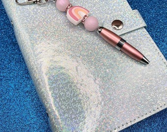Hues of pink rainbow & round iridescent white/pink silicone beads on metallic pink pen casing with black ink + pink rhinestones + clip.