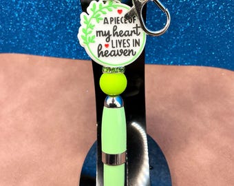 Green, black & white “ A Piece of My Heart Lives In Heaven” + round green silicone beads on green pen casing with black ink + clip.