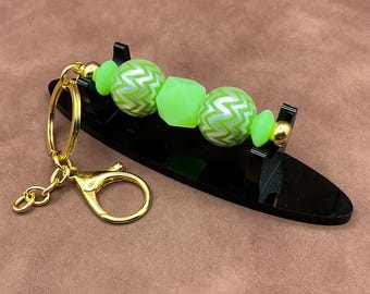 Gold hardware and post with clip keychain/zipper. Acrylic green round balls with green hexagonal silicone bead and green spacers.