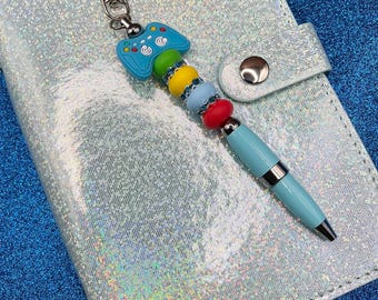 Blue Game Controller + oval green, yellow, blue + red silicone beads on blue pen casing with black ink + blue rhinestone spacers + clip.