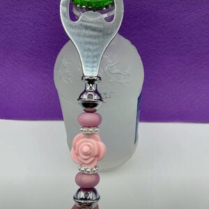 May include: A silver bottle opener with a pink rose and pearl bead embellishment.