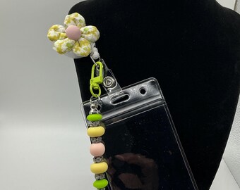 Fabric flower retractable lanyard with clear ID sleeve. Green ,yellow, pink silicone beads with gun metal rhinestone spacers with green clip
