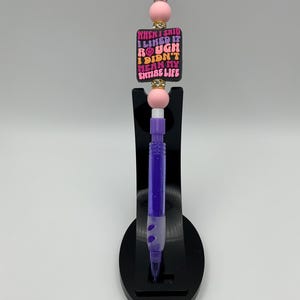 May include: Purple and pink beaded pen with a black charm that says "When I said I liked it rough I didn't mean my entire life".