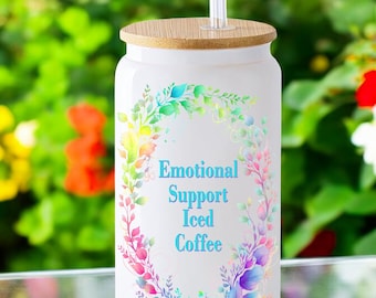 May include: White tumbler with a bamboo lid and a clear straw. The tumbler has a colorful floral design and the text "Emotional Support Iced Coffee".