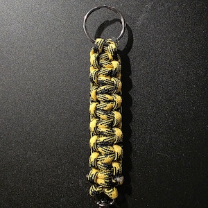 May include: A black and yellow paracord keychain with a silver key ring and a silver clip.