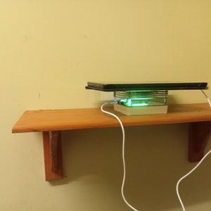 May include: A white charging stand with a green light, a black tablet on top, and a white charging cable.