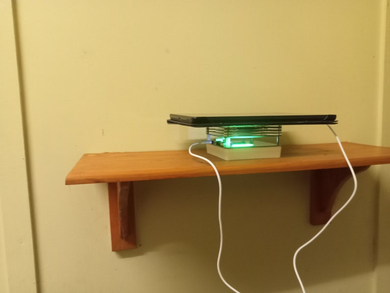 May include: A white charging stand with a green light, a black tablet on top, and a white charging cable.