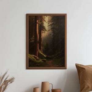 Op de afbeelding: Een ingelijste kunstdruk met een dicht boslandschap met hoge mammoetbomen, bemoste grond en zacht licht dat door het bladerdak filtert. Het kunstwerk zit in een eenvoudige bruine houten lijst en hangt aan een effen witte muur.