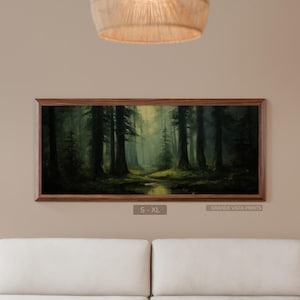 May include: A framed landscape painting depicts a misty forest scene. Tall, dark trees dominate the foreground, with a stream of water and a soft light in the distance. The frame is a dark wood. The text "S - XL" and "GRANDE VISTA PRINTS" are visible.