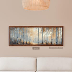 May include: A framed landscape print depicting a misty forest scene with tall, slender trees. The artwork features a palette of soft blues, golds, and browns, creating a serene and natural ambiance. The frame is a warm brown color. The text "S - XL" and "GRANDE VISTA PRINTS" are visible.