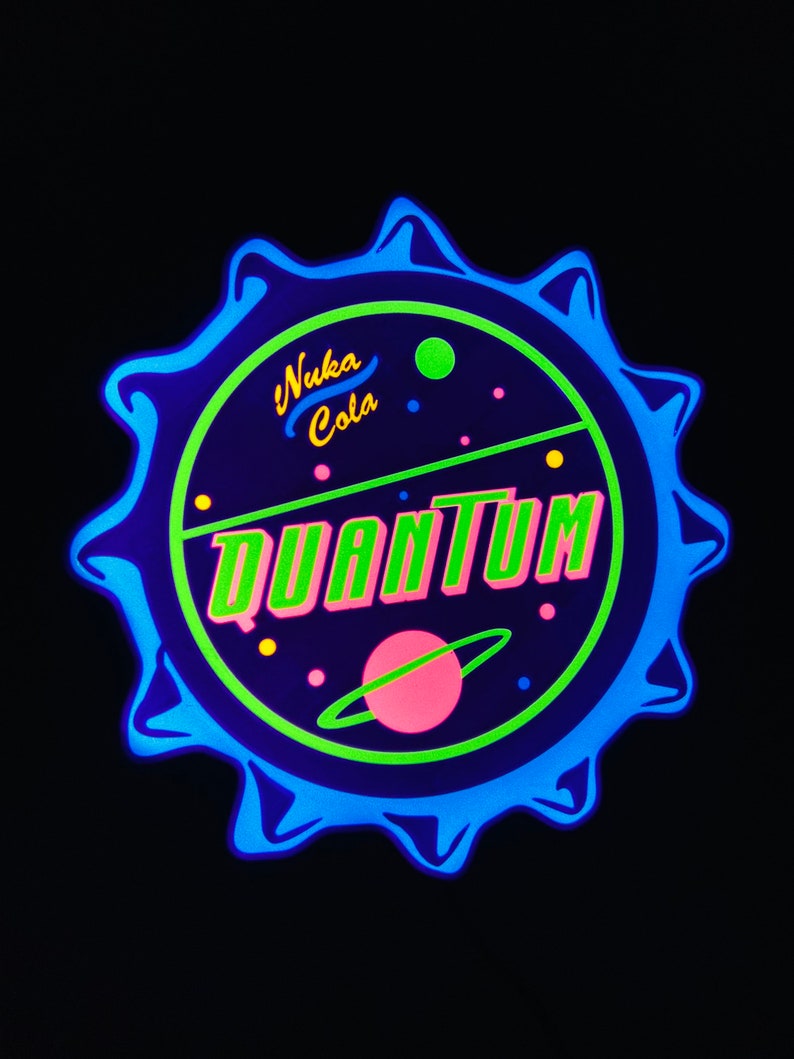 May include: A neon sign featuring the Nuka Cola Quantum logo. The design is a stylized bottle cap with a blue outline and a dark blue center. The text "Nuka Cola" is in yellow and blue, and "QUANTUM" is in green and pink, with a pink planet.