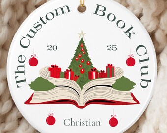 May include: White ceramic Christmas ornament with gold string. The ornament features a Christmas tree, gifts, and an open book. Text includes "The Custom Book Club", "20", "25", and "Christian". Red and green accents.