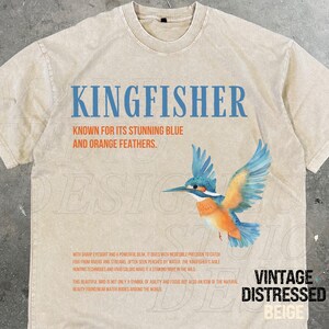 Puede incluir: Camiseta beige con un aspecto vintage desgastado que presenta un gr&aacute;fico de un mart&iacute;n pescador con plumas azules y naranjas. El texto "KINGFISHER" est&aacute; impreso en azul sobre el p&aacute;jaro. El texto "KNOWN FOR ITS STUNNING BLUE AND ORANGE FEATHERS." est&aacute; impreso en negro debajo del p&aacute;jaro. El texto "VINTAGE DISTRESSED BEIGE" est&aacute; impreso en negro en la esquina inferior derecha de la camiseta.