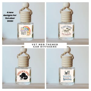 May include: Four clear glass car diffusers with wooden caps and hanging ropes. Each bottle features a unique graphic label: a golden retriever with a rainbow, a skeleton dog, a black cat, and a husky. Text includes "It's not all rainbows & butterflies", "It just started this morning", "Gabbies for the crabbies", and "Trazzies for the spazzies".