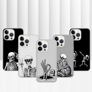 May include: A collection of phone cases with skeleton designs. The cases are black, white, and gray, featuring various skeleton illustrations. One case has the text "I'M OKAY" on a tombstone.