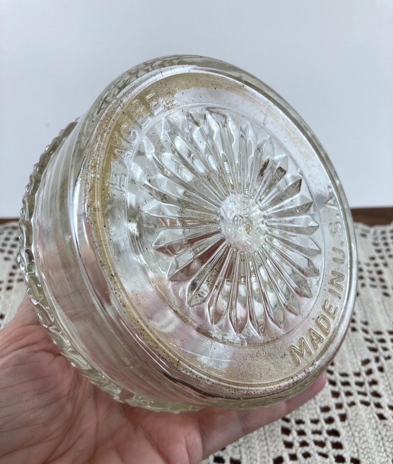 May include: Clear glass bowl with a decorative, starburst-patterned base. The bowl's rim has a textured design. The words "MADE IN U.S.A." are visible on the base. The bowl is likely vintage.