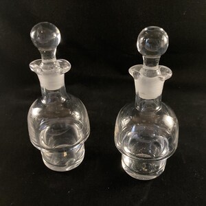 May include: Two clear glass bottles with stoppers. The bottles have a textured, rounded design and are perfect for holding oil or vinegar.