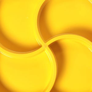 May include: Bright yellow interlocking plastic mold for creating a four-leaf clover shape. The mold is made of durable plastic and is designed for use in landscaping or crafting projects. The design features four circular sections that interlock.