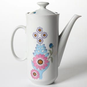 May include: White ceramic coffee pot with a lid and handle. The pot is decorated with a floral design in pink, purple, blue, and yellow. The spout is long and slender.