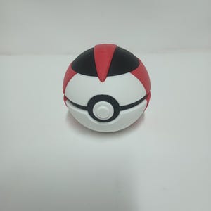 May include: A white, red, and black Pok&eacute; Ball. The top section is red and black, with a white center and a black band. The button is white. This collectible item is a popular choice for fans of the animated series.