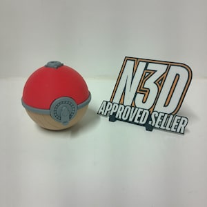 May include: A red and tan sphere with a gray button and a gray top. Next to it is a sign that says "N3D APPROVED SELLER" in black, orange, and white.