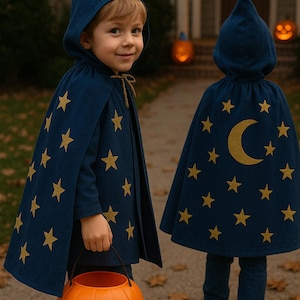 Peut inclure: Deux enfants vêtus de capes de sorcier bleu marine ornées d'étoiles et d'une lune dorées, tenant un seau citrouille orange. Les capes ont des capuches assorties. Ils marchent sur un trottoir, probablement pour Halloween.