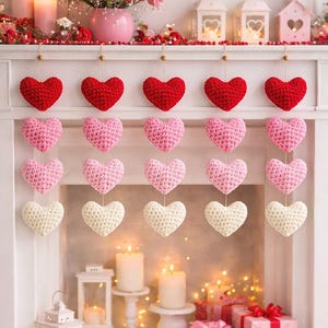 May include: A decorative display featuring rows of crocheted hearts in red, pink, and cream colors. The hearts are suspended in front of a fireplace mantel decorated with candles, flowers, and gift boxes, creating a romantic ambiance.