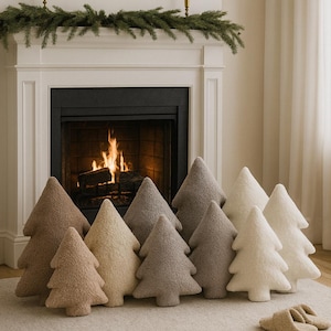 Peut inclure: Plusieurs coussins en forme d'arbres de différentes couleurs neutres, disposés devant une cheminée. Les coussins varient du beige clair au marron foncé. Une paire de pantoufles moelleuses est posée sur le tapis.