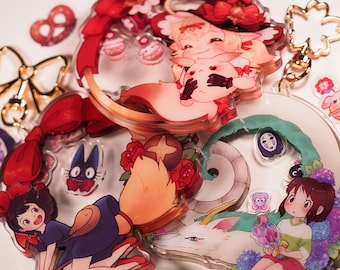 以下が含まれることがあります： アニメスタイルのキャラクターが描かれた、カラフルなアクリルチャームのコレクション。魔女、黒猫、その他のファンタジーのキャラクターの画像が含まれています。一部のチャームには、金色のキーホルダーが付いています。