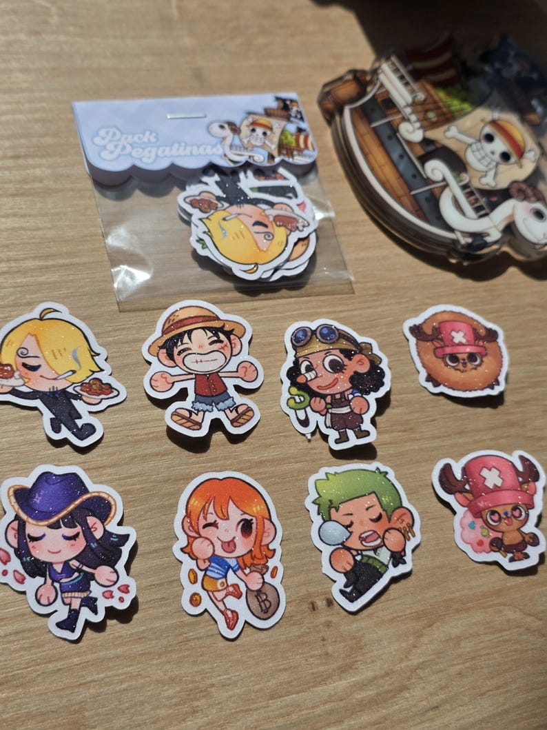 Op de afbeelding: Een verzameling kleurrijke stickers met personages uit de anime-serie One Piece. De stickers tonen verschillende personages in chibi-stijl, met een pakje stickers in een plastic hoesje met de tekst "Pack Pegatinas".