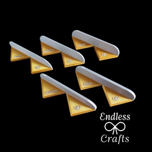 May include: Five white plastic corner pieces with gold accents. Each piece has a different measurement in millimeters: 2mm, 2.5mm, 3.5mm, 4mm, and 4mm. The pieces are labeled with the measurements in white text. The pieces are arranged in a staggered pattern on a black background. The text "Endless Crafts" is printed in white below the pieces.