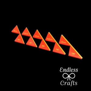 Könnte beinhalten: Eine Sammlung roter und goldener dreieckiger Werkzeuge, die jeweils mit einem Maß in mm beschriftet sind. Die Werkzeuge sind diagonal vor einem schwarzen Hintergrund angeordnet. Der Text "Endless Crafts" befindet sich unten rechts.