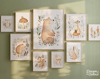 May include: Set of 10 watercolor illustrations featuring woodland animals and plants. The illustrations are framed in a light wood frame and are arranged in a grid pattern on a green wall. The illustrations include a bear, a fox, a hedgehog, a squirrel, a deer, a butterfly, an owl, a mushroom, and a rabbit.