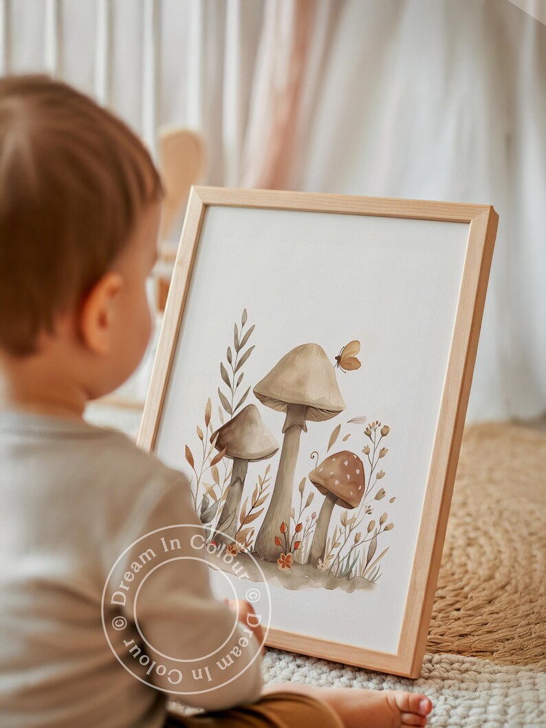 May include: A framed watercolor print featuring three mushrooms in shades of brown and beige, with a small butterfly and foliage. The artwork is in a light wooden frame. The text "Dream In Colour" is visible on the bottom of the print.
