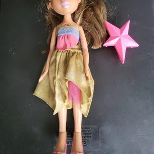 Bratz Yasmin fully dressed in gold and pink skirt, pink and blue top, pink heels and pink star brush.