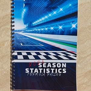 Könnte beinhalten: Ein spiralgebundenes Notizbuch mit einem Cover, das eine Formel-1-Rennstrecke zeigt. Das Cover ist überwiegend blau, mit dem Text "2026 Season Statistics Formula Racing" in Weiß und Rot. Das Notizbuch liegt auf einer beigen Oberfläche.