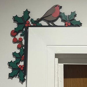 Peut inclure: Décoration d'angle en bois représentant un rouge-gorge perché sur une branche de houx. Le rouge-gorge a une poitrine rouge et des plumes brunes. Le houx a des feuilles vertes et des baies rouges. Pour un cadre de porte.