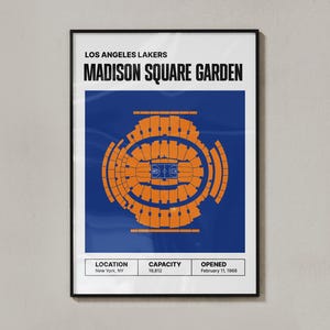 May include: A framed poster featuring a top-down view of Madison Square Garden in orange against a blue background. The text "LOS ANGELES LAKERS" and "MADISON SQUARE GARDEN" are at the top. Below are details: Location, Capacity, and Opened date.