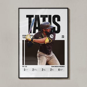 Puede incluir: Póster enmarcado con el jugador de béisbol Fernando Tatis Jr. con el uniforme de los Padres, bateando. El póster incluye el nombre "TATIS" en letras grandes, junto con estadísticas y el texto "SAN DIEGO PADRES". La combinación de colores es marrón, negro y blanco.