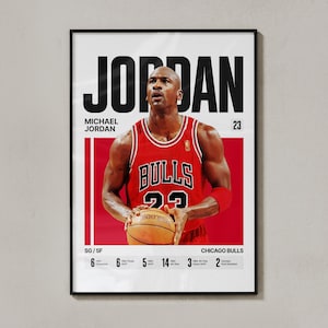 May include: A framed poster featuring Michael Jordan in a red Chicago Bulls jersey, holding a basketball. The poster includes the name "JORDAN" in large black letters, along with statistics and the team name.