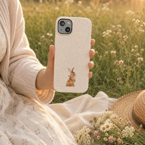 Bow bunny phone case held outdoors in a wildflower field