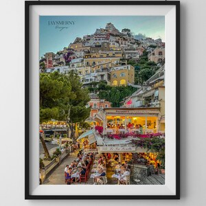 May include: A colourful cityscape with buildings on a hillside overlooking a restaurant with people dining outdoors. The restaurant is called "La  Terrazza" and has a sign with the words "Ristorante La  Terrazza" in Italian.