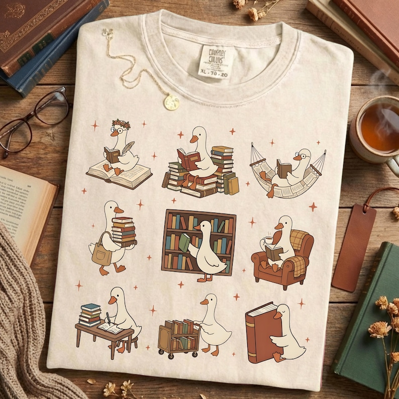 Puede incluir: Camiseta de color crema con un dise&ntilde;o caprichoso de gansos de dibujos animados leyendo libros en varios entornos. Los gansos est&aacute;n representados con gafas y accesorios, rodeados de libros y muebles. La camiseta tiene el texto "CAMPY COLORS" y la talla "XL 70-20".