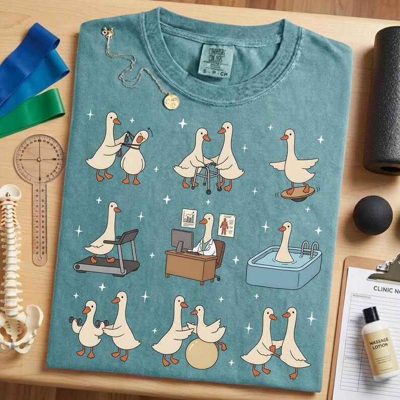 Pode incluir: Camiseta azul-petr&oacute;leo com gansos de desenho animado em v&aacute;rios cen&aacute;rios de fisioterapia. Os gansos s&atilde;o retratados usando uma esteira, prancha de equil&iacute;brio e outros equipamentos de reabilita&ccedil;&atilde;o. Uma pequena etiqueta na camisa diz "Comfort Colors". Um colar de ouro est&aacute; sobre a camisa.