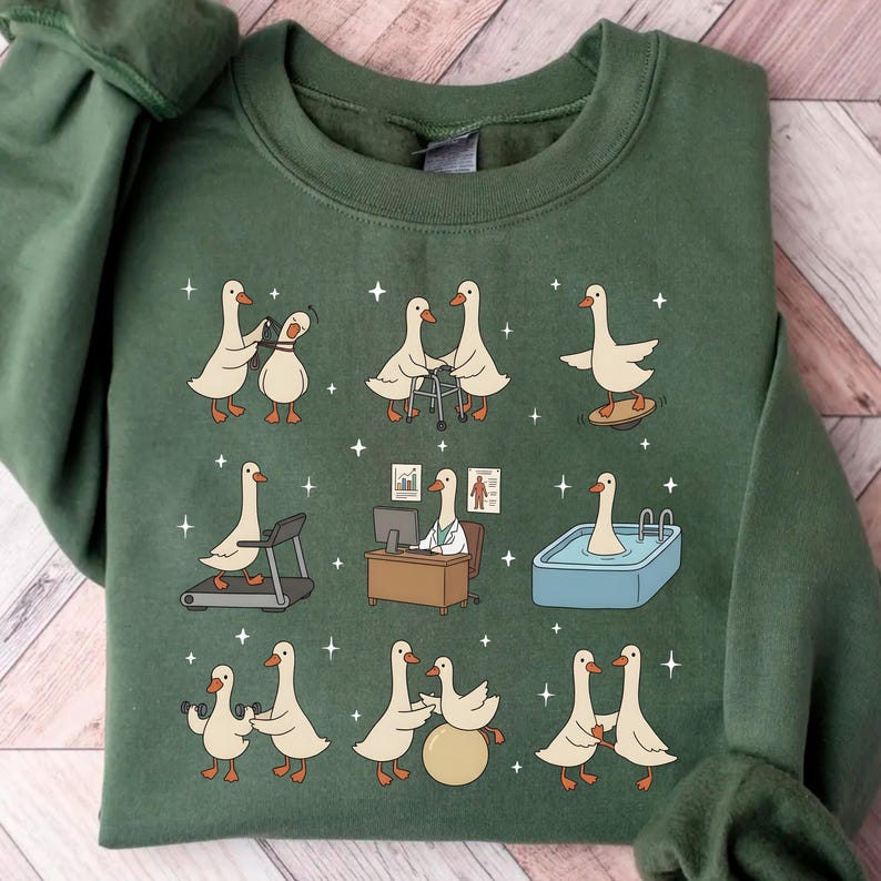 Pode incluir: Camisola verde com um design caprichoso com gansos de desenho animado em v&aacute;rias atividades, incluindo boliche, usando um andador e fazendo exerc&iacute;cios. Os gansos s&atilde;o retratados em uma esteira, em uma mesa e em uma piscina. Estrelas brancas espalhadas.