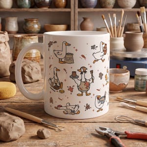 May include: A white ceramic mug featuring a repeating pattern of cartoon ducks engaged in pottery activities, including holding clay bags, shaping pots, and using tools, accented with small brown splatters and star shapes.
